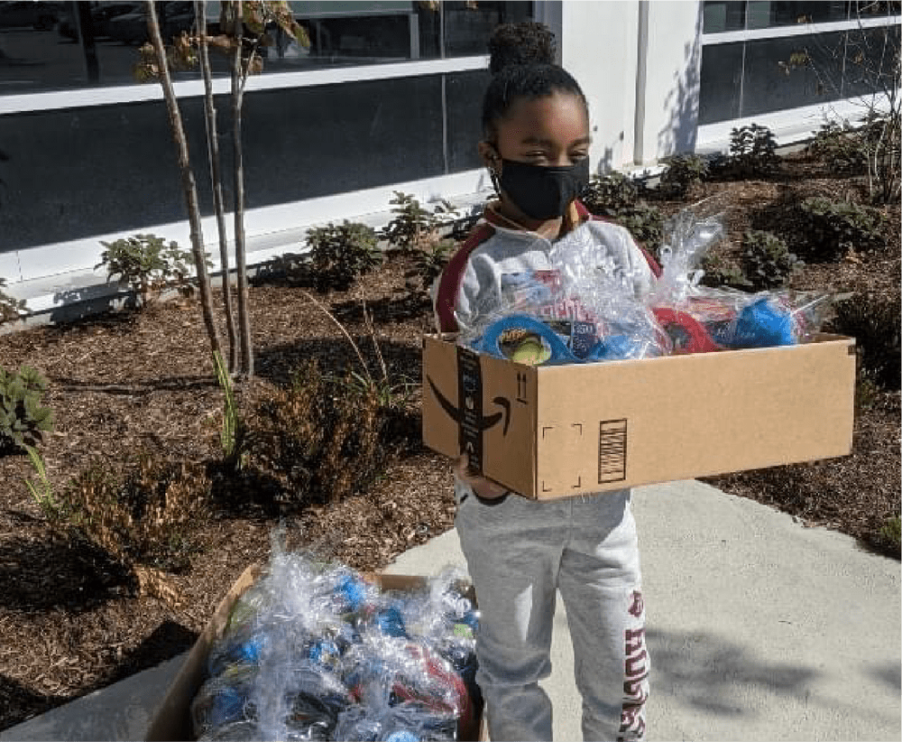 Little girl holding a box filled with gift bags and toys for other children